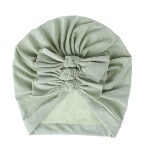 Detail shot of soft knit infant turban hat with cute bows, lightweight baby headwear.