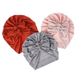Close-up detail of soft knit baby turban hat with pleated bow, comfortable infant headwear.