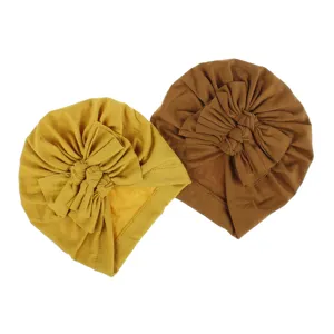 Detailed view of soft knitted baby turban hats with cute bow knots in yellow and brown.