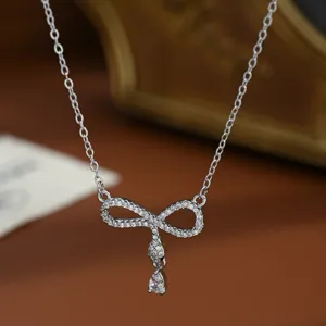 Exquisite micro-pavé zirconia bow infinity necklace detail, elegant silver clavicle chain.