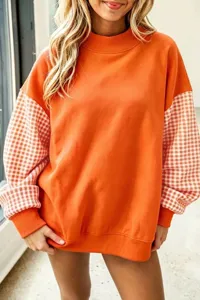 Vista detallada de la sudadera de felpa naranja para mujer con mangas a cuadros contrastantes.