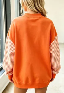 Vista detallada de la sudadera naranja con cuello alto y mangas de cuadros elegantes.