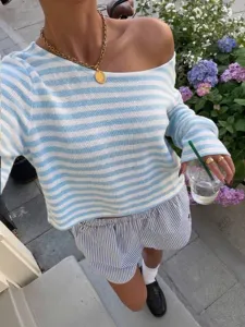 Gedetailleerd overzicht van blauw-witte gestreepte gebreide top met lange mouwen buiten.