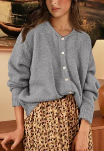 Detail view of a cozy grey knit cardigan featuring a crewneck, long sleeves, and buttons.