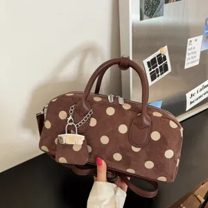 Brown suede polka dot handbag with top handles, chic shoulder strap and mini bag charm detail.