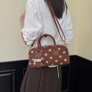 Brown polka dot shoulder bag, casual everyday handbag with top handles and charm detail.