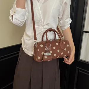 Brown polka dot cylinder shoulder bag detail showing soft suede texture and elegant design.