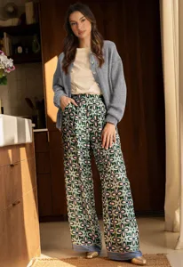 Detailed view of women's casual loose button knit cardigan in cozy indoor home scene.