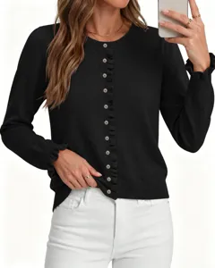 Detailopname van het zwarte gebreide vest met delicate volantranden en lange mouwen.