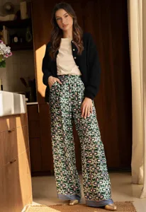 Cozy knit cardigan and patterned wide leg pants outfit detail in modern kitchen interior.