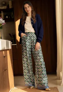 Detailed view of the stylish women's knit cardigan and printed trousers in a warm kitchen setting.