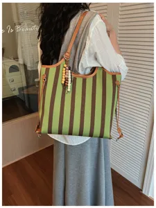 Borsa tote in tela a righe verdi e marroni con dettagli in pelle e ciondoli di perline di legno.
