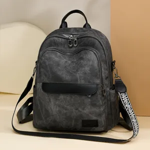 Primo piano dettagliato dello zaino in tela grigio scuro con doppie zip e tracolla fantasia.