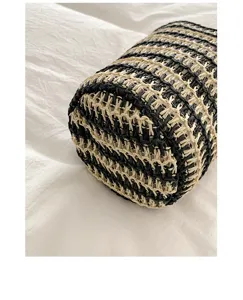 Nahaufnahme der handgemachten schwarz-weißen gestreiften Stroh-Eimer-Tasche für den Strandurlaub.