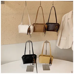 Detailansicht der minimalistischen PU Leder Umhängetasche mit Perlenanhänger und verschiedenen Farben.