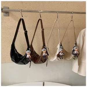 Gedetailleerd overzicht van stijlvolle slouchy halvemaan schoudertassen hangend met schattige poppen.