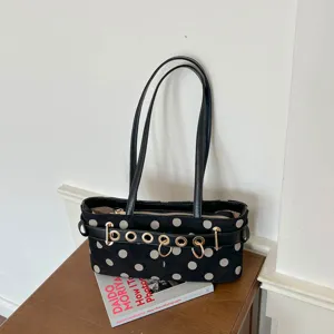 Dettaglio di borsa a spalla nera a pois, con manici in pelle nera e anelli metallici eleganti.