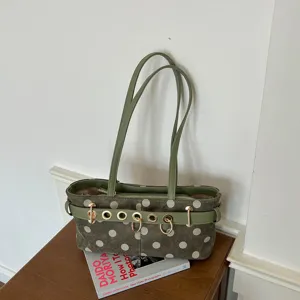 Vista dettagliata della borsa a spalla verde oliva a pois con decorazione di anelli metallici.
