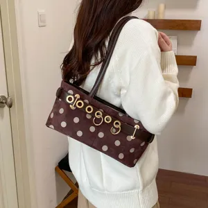 Vista dettagliata di una borsa a tracolla marrone a pois con fibbie e cinturino in pelle.