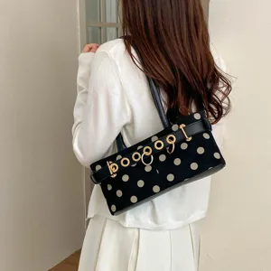 Vista dettagliata di una elegante borsa a spalla nera a pois con dettagli di anelli metallici.
