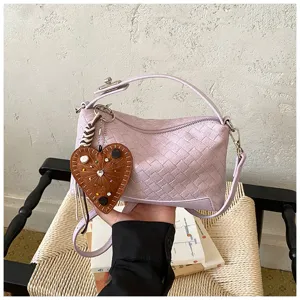 Vue détaillée du sac porté épaule en cuir tissé mauve pastel avec un charmant pendentif en cœur.