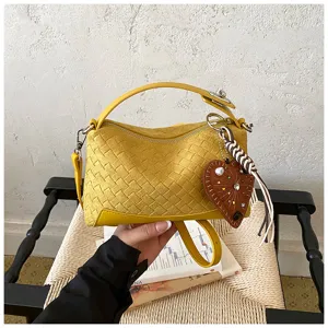 Vista dettagliata della borsa a mano intrecciata gialla con ciondolo a cuore chic e finitura.