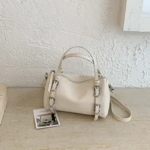 Vista dettagliata della borsa a mano cilindrica beige con fibbie, ottima fattura.