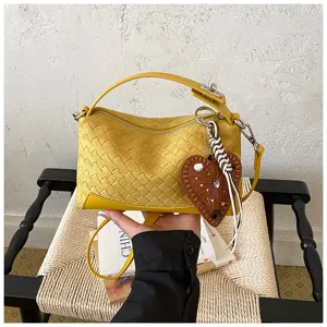 Vue détaillée du sac à bandoulière tissé jaune élégant, montrant un savoir-faire exquis.