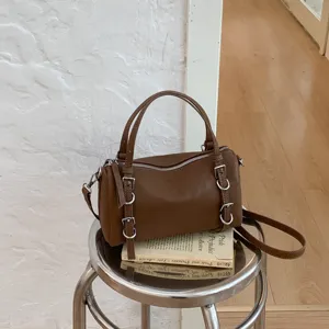 Borsa a tracolla cilindrica vintage marrone con doppi manici e fibbie decorative.