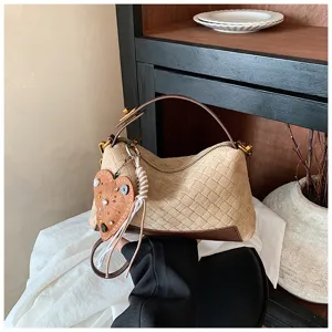 Gros-plan du sac à main en daim tissé vintage avec joli pendentif en cœur et bandoulière.