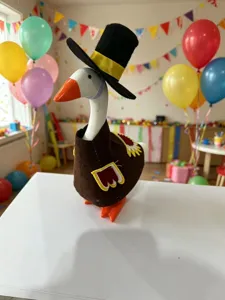 Close-up of a desktop decorative goose wearing a Thanksgiving turkey costume and top hat.