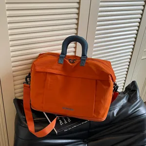 Dettaglio della borsa da viaggio con tessuto arancione, manici blu e spazio di archiviazione.