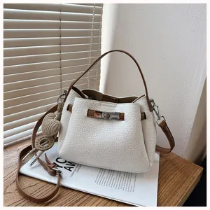 Détail de sac seau blanc et marron chic, doté d'une élégante fermeture tourniquet et texture.