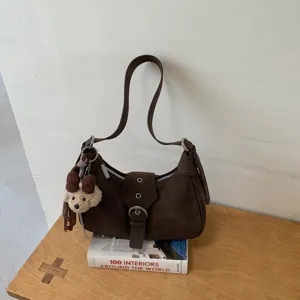 Vista detallada del bolso hobo de ante marrón con un lindo llavero de perrito y hebilla.