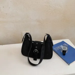 Vista detallada de un bolso de hombro negro minimalista con elegante hebilla frontal.