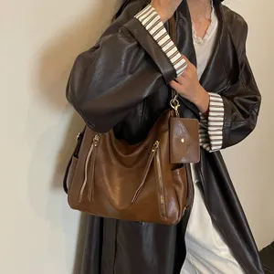 Brown leather shoulder bag tote with double vertical zippers and small purse pendant for women.