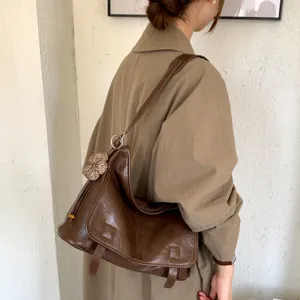 Dettaglio borsa a tracolla in pelle marrone retrò, borsa vintage indossata dalla modella.