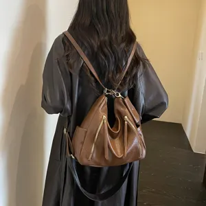Detailed view of brown leather commuter backpack, stylish multi-zipper design for daily wear.