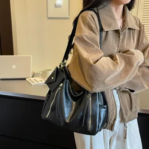 Detail view of black women shoulder tote bag, stylish commuter handbag with metal zippers.