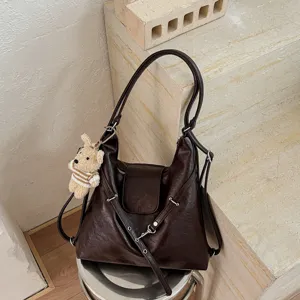 Vista detallada del bolso mochila marrón oscuro con bonito colgante de oso y detalles.
