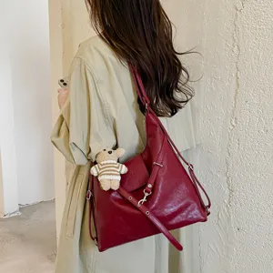 Elegante bolso de hombro hobo de cuero suave rojo oscuro con lindo colgante de oso para mujeres.