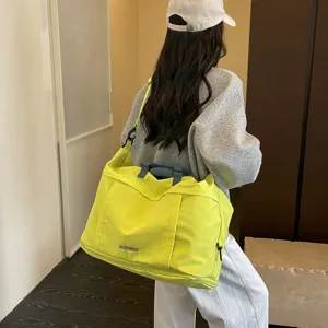Vista dettagliata della borsa da viaggio giallo fluo con manici grigi, stile quotidiano.