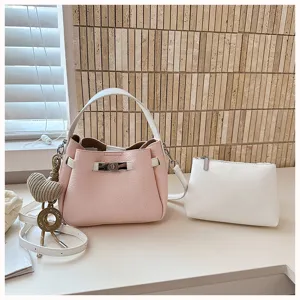 Vue détaillée du sac seau rose tendance avec poignée blanche et pochette accessoire.