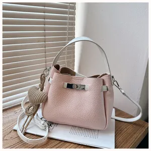 Sac seau rose élégant pour femme avec poignée supérieure, charm cœur tissé et bandoulière.
