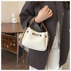 Sac seau élégant en cuir blanc avec poignées marron et fermeture tournante pour le quotidien.