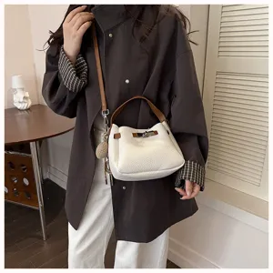 Détail du sac seau blanc texturé avec poignée marron, style bandoulière élégant.