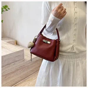 Détail en gros plan d'un sac seau rouge pour femme en cuir texturé avec un fermoir tournant.