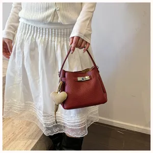 Sac seau rouge en cuir grainé avec serrure métallique, sac à main bandoulière élégant pour femme.
