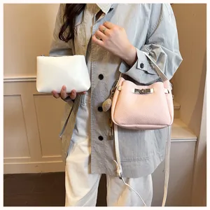 Sac seau élégant pour femme en détail, sac bandoulière en cuir rose avec petite pochette blanche.