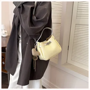 Vue détaillée du sac seau jaune élégant porté, montrant sa texture et ses ferrures.